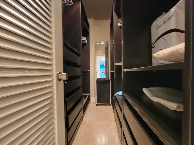 a walk in closet with wooden floor