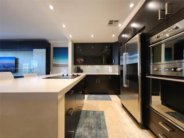 a large kitchen with a large counter top stainless steel appliances and cabinets