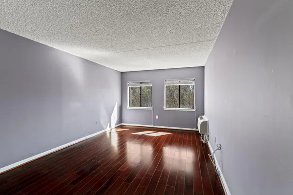 a view of an empty room with wooden floor and windows