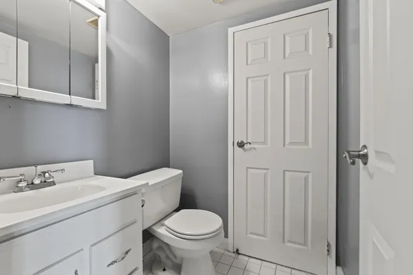 a bathroom with a toilet sink vanity and mirror