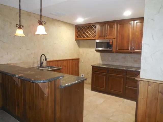 a kitchen with stainless steel appliances granite countertop a sink a microwave oven and a refrigerator with wooden cabinets