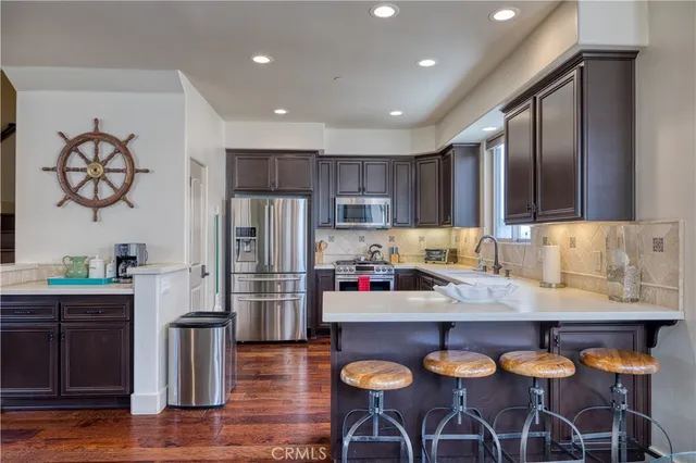a kitchen with stainless steel appliances granite countertop a sink a stove a refrigerator cabinets and living room view