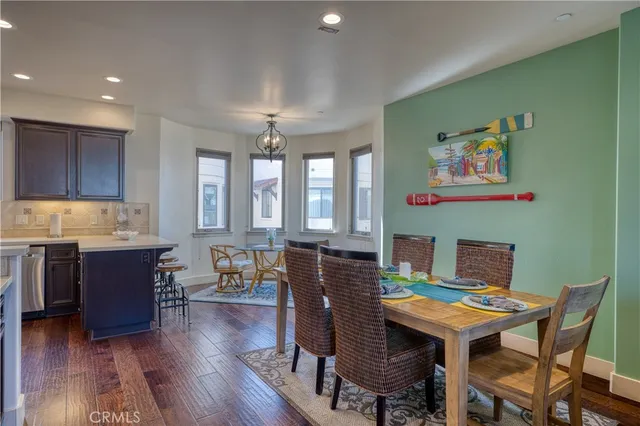 a open kitchen with stainless steel appliances granite countertop a stove top oven a sink dishwasher and white cabinets with wooden floor