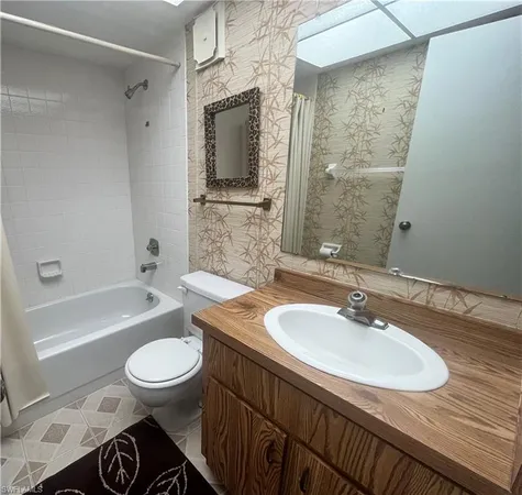 a bathroom with a granite countertop sink a toilet a mirror and shower