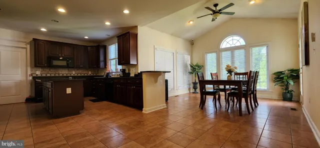 a kitchen with stainless steel appliances granite countertop a stove top oven a sink a dining table and chairs