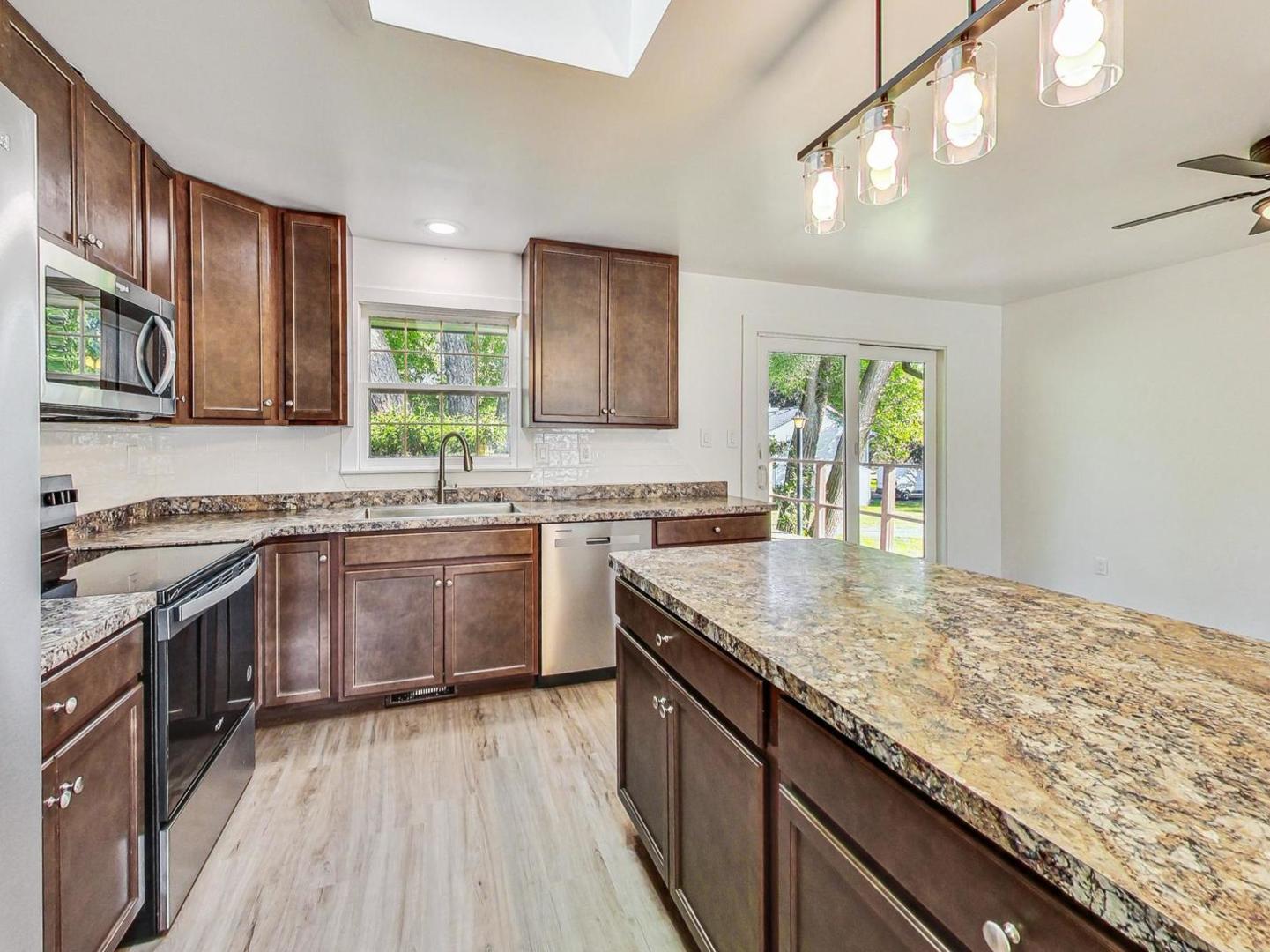 4618 William Street Johnsburg, IL 60051 - Photo 5 of 40 a kitchen with stainless steel appliances granite countertop wooden cabinets a stove top oven a sink and dishwasher with wooden floor