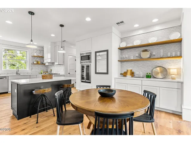 a kitchen with stainless steel appliances kitchen island granite countertop a table chairs and a refrigerator
