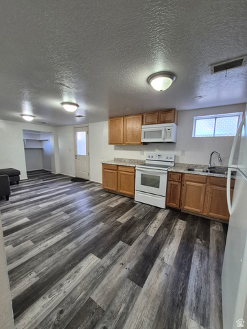 327 North 300 West Logan, UT 84321 - Photo 8 of 12 Kitchen featuring wood finish cabinetry, white appliances, dark wood-style flooring, and a textured ceiling