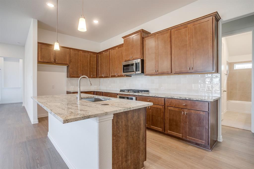 909 Schuberts Road Justin, TX 76247 - Photo 5 of 34 a kitchen with stainless steel appliances granite countertop a sink a stove a refrigerator and cabinets