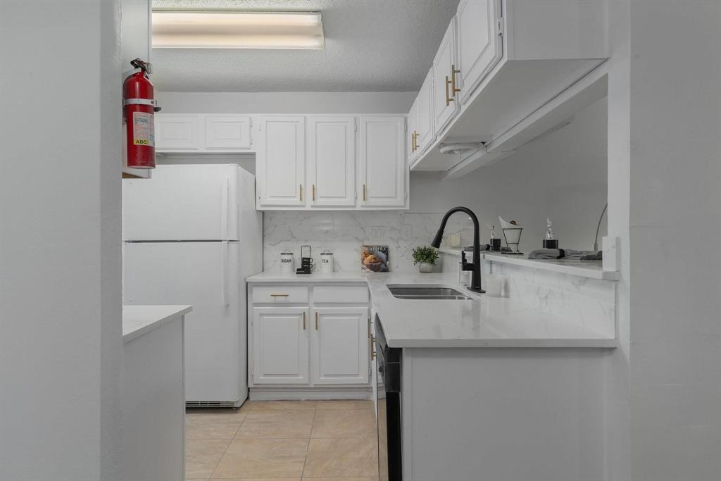 5981 Arapaho Road, Unit 305 Dallas, TX 75248 - Photo 22 of 38 a kitchen with sink a refrigerator and cabinets