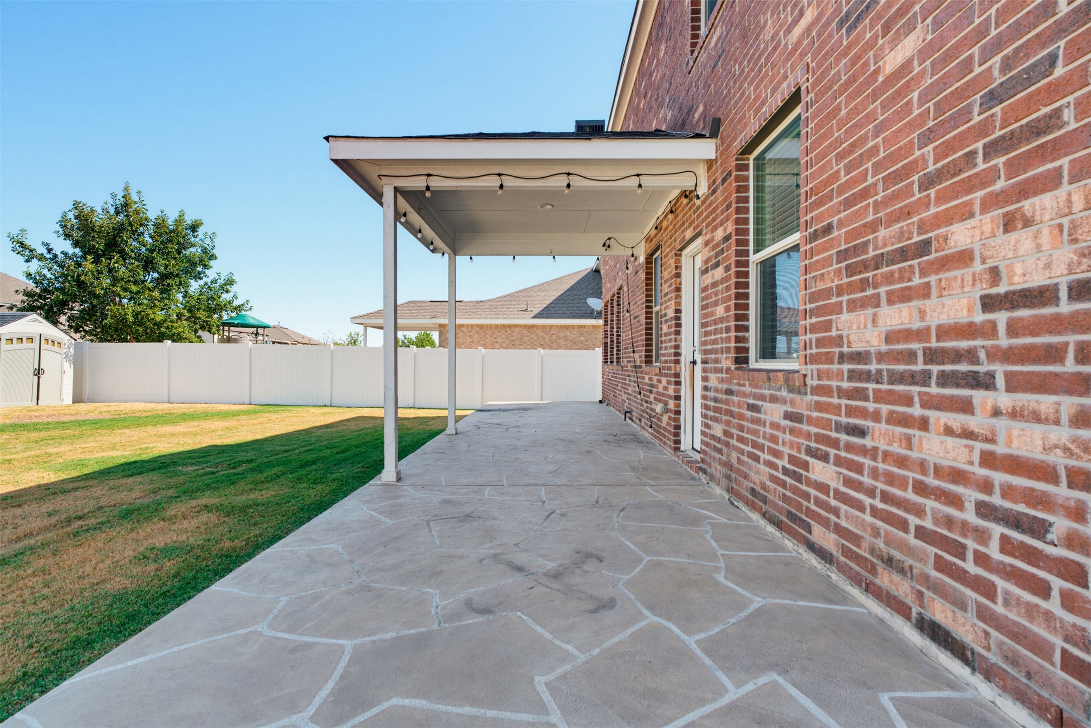11008 Players Path Austin, TX 78747 - Photo 23 of 26 A spacious covered patio with stone-patterned concrete flooring overlooks the grassy backyard.