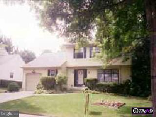 a front view of a house with garden and trees