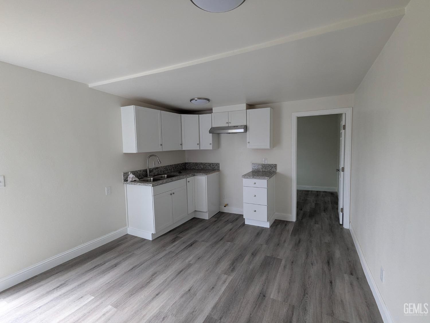 Undisclosed Address Bakersfield, CA 93307 - Photo 11 of 17 a kitchen with wooden floors and white appliances