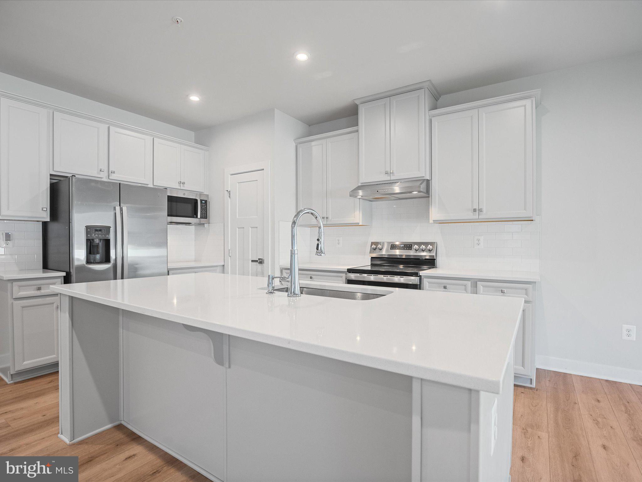 303 Pathfinder Circle Grasonville, MD 21638 - Photo 10 of 38 a kitchen with a sink a stove a refrigerator and white cabinets