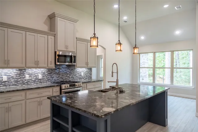 a kitchen with kitchen island granite countertop a sink a counter space appliances and cabinets