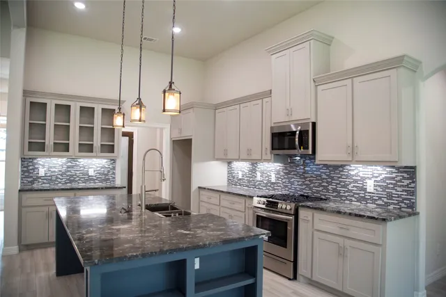 a kitchen with stainless steel appliances granite countertop a kitchen island a stove and a sink