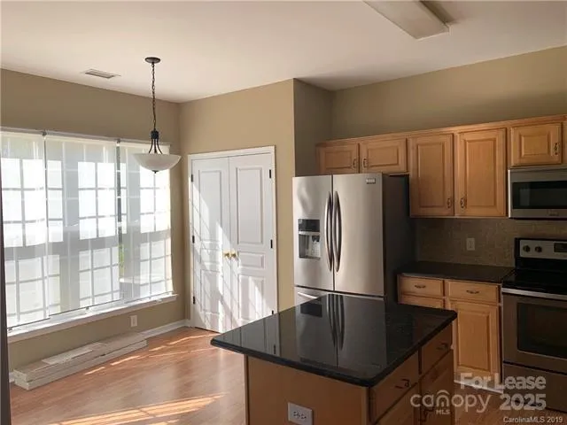 a kitchen with stainless steel appliances granite countertop a refrigerator a stove and a sink with granite countertops