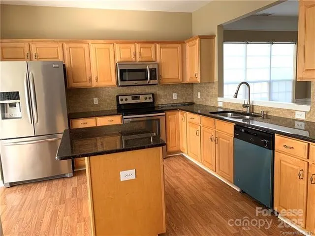 a kitchen with granite countertop a refrigerator stove and sink