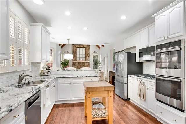 a large kitchen with stainless steel appliances granite countertop a stove a sink dishwasher and a refrigerator with wooden floor