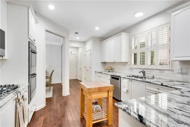 a kitchen with stainless steel appliances a refrigerator a sink a stove a dining table and chairs