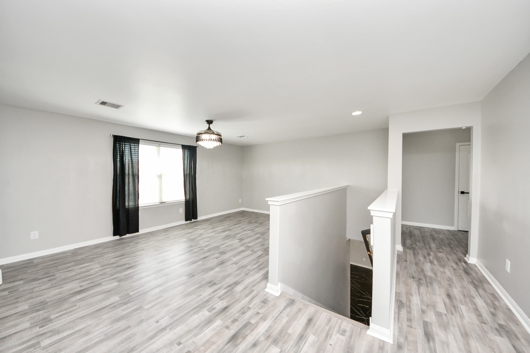 6931 Primrose Road Baytown, TX 77521 - Photo 29 of 50 Spacious upstairs game room with wood-look flooring, neutral tones, and a large window bringing in natural light—perfect for a second living area or entertainment space.