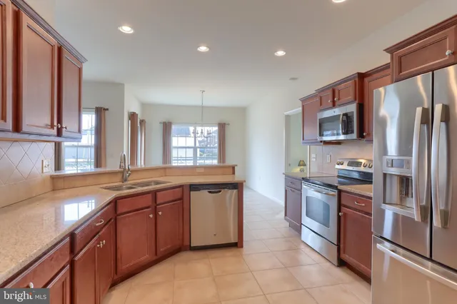 a kitchen with stainless steel appliances granite countertop a sink a stove and a refrigerator