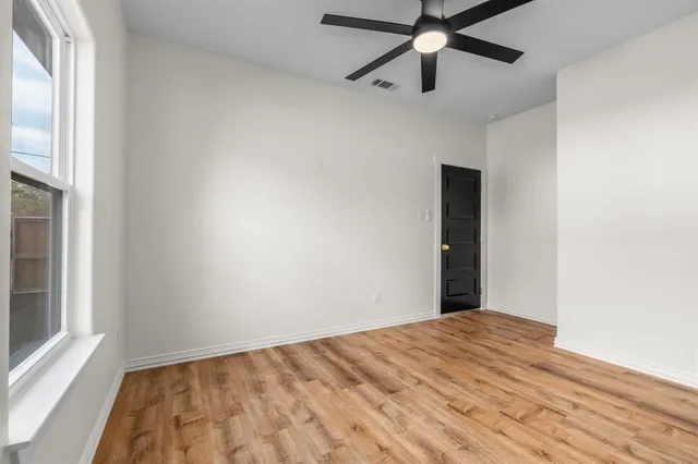 an empty room with a window and a fan