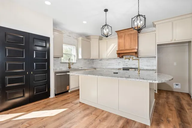 a kitchen with kitchen island granite countertop a sink cabinets and stainless steel appliances