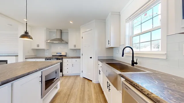 a kitchen with stainless steel appliances granite countertop a sink a stove and a wooden floors