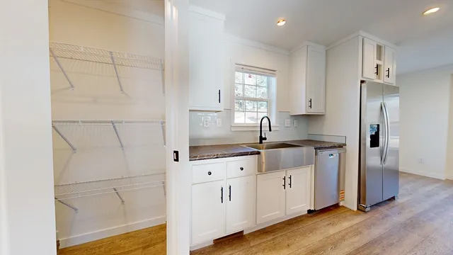a kitchen with granite countertop white cabinets and refrigerator