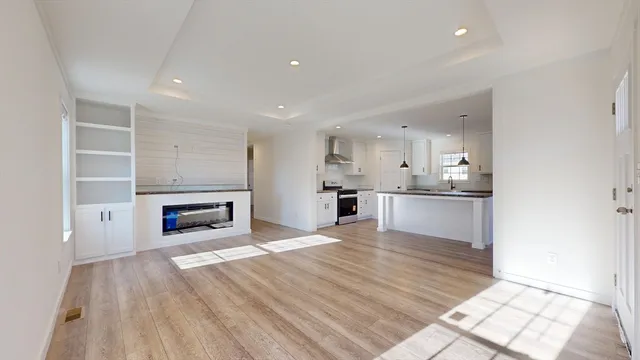 a large white kitchen with kitchen island a sink dishwasher and a stove with wooden floor