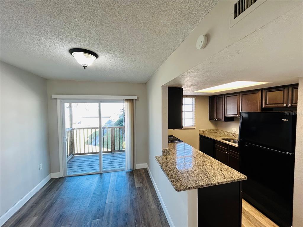 2791 L B McLeod Road, Unit D Orlando, FL 32805 - Photo 5 of 13 a kitchen with granite countertop kitchen island a refrigerator a stove a sink dishwasher and wooden cabinets with wooden floor
