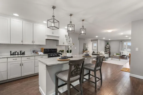 a kitchen with stainless steel appliances kitchen island granite countertop a dining table chairs and white cabinets