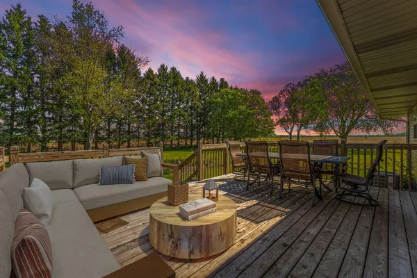 a view of a roof deck with dining table and chairs with wooden floor and fence