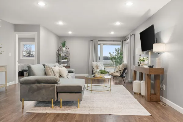 a living room with furniture a flat screen tv and a large window