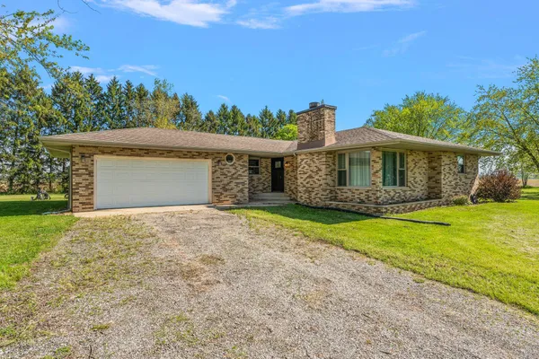 a view of a house with a big yard plants and large tree