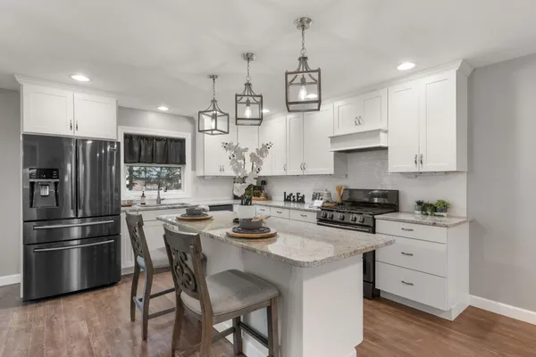 a kitchen with stainless steel appliances a stove a sink a refrigerator and white cabinets