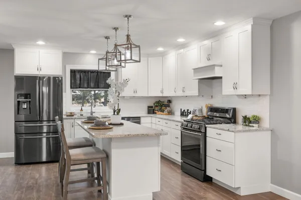 a kitchen with kitchen island a sink stove a refrigerator and white cabinets