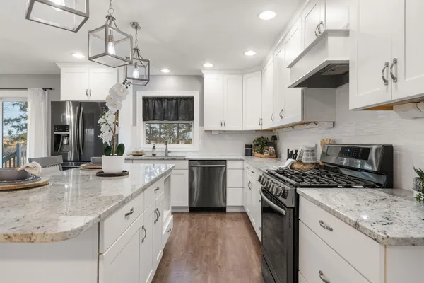 a kitchen with stainless steel appliances granite countertop a sink a stove top oven a counter space and cabinets