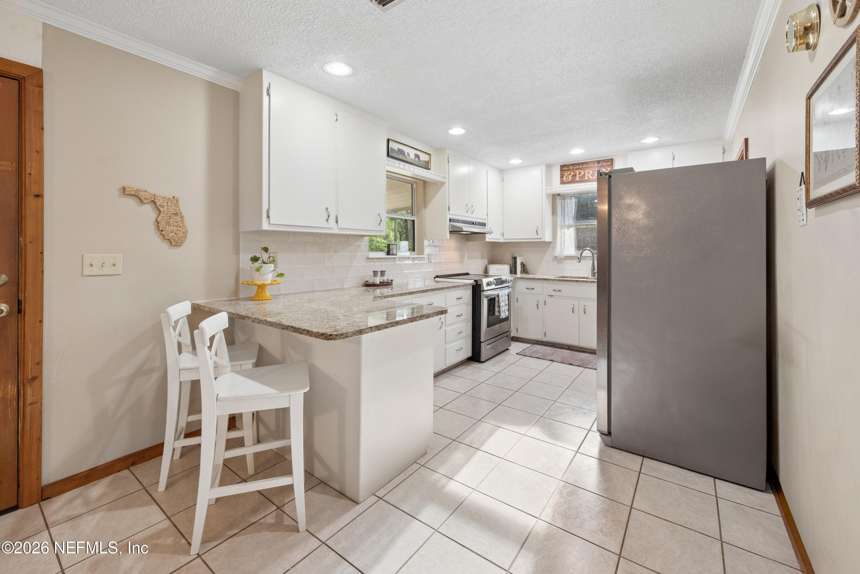 20021 Southeast 88th Trail Lake Butler, FL 32054 - Photo 23 of 43 a kitchen with a dining table chairs refrigerator and cabinets