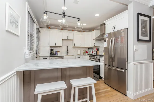 a kitchen with stainless steel appliances granite countertop a refrigerator a sink dishwasher a stove and white cabinets with wooden floor