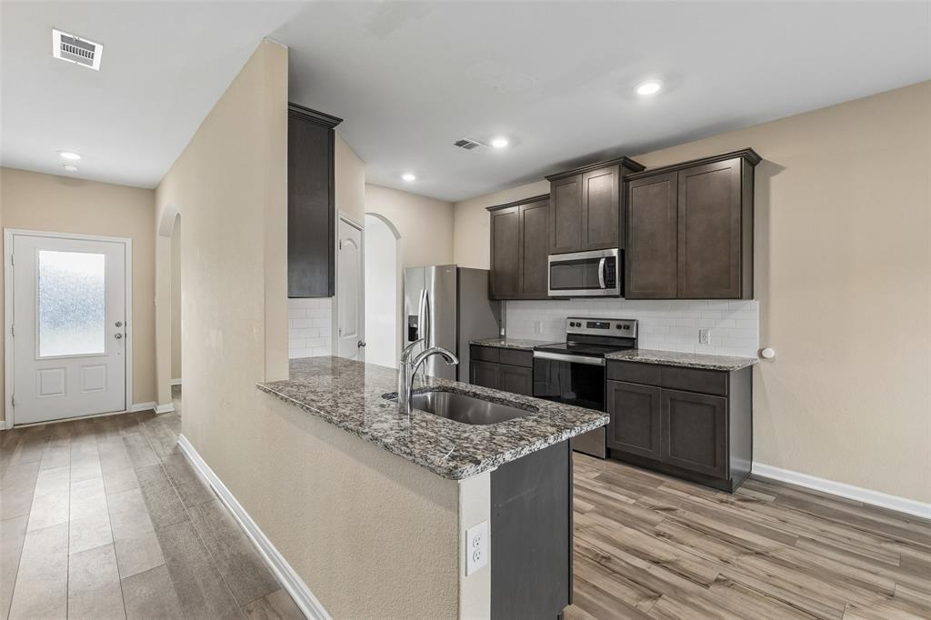 230 Enchanted Way Princeton, TX 75407 - Photo 5 of 31 a kitchen with kitchen island granite countertop stainless steel appliances and wooden cabinets