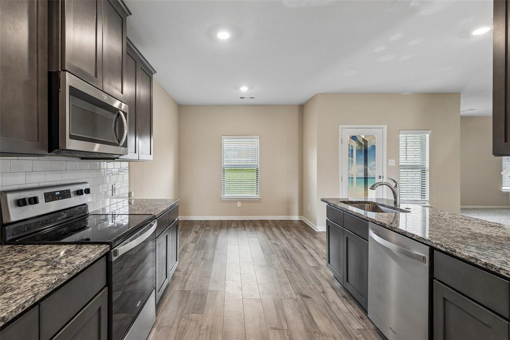 230 Enchanted Way Princeton, TX 75407 - Photo 6 of 31 a kitchen with granite countertop stainless steel appliances a sink stove top oven and cabinets