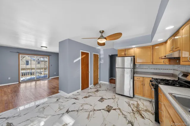 a kitchen with stainless steel appliances kitchen island granite countertop a refrigerator and a stove top oven