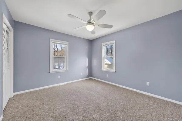 an empty room with windows and ceiling fan