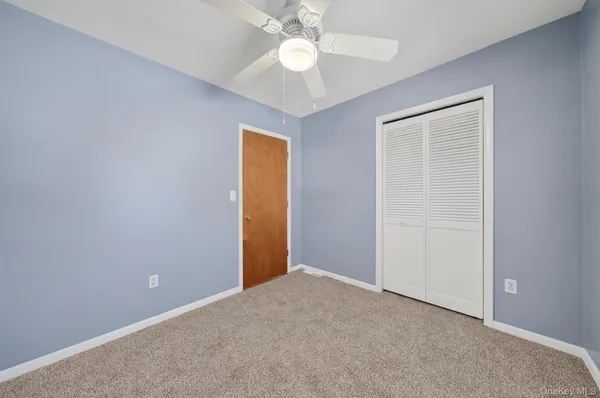 an empty room with closet and a chandelier fan
