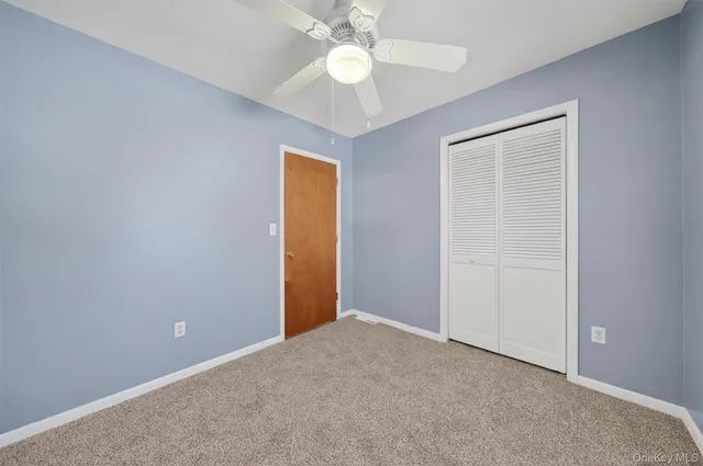 an empty room with closet and a chandelier fan
