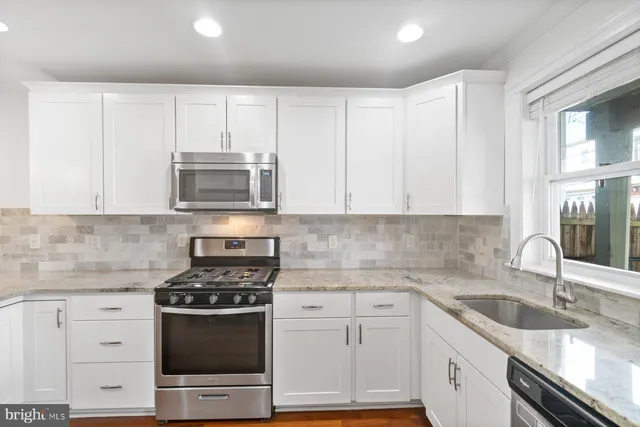 a kitchen with granite countertop white cabinets and appliances