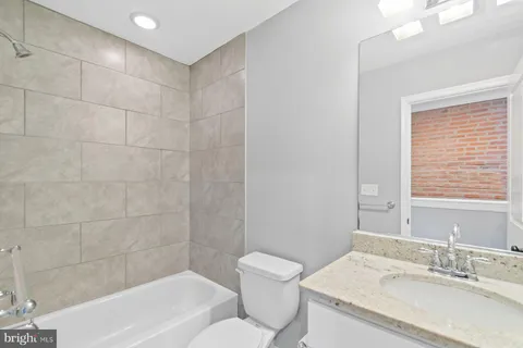a bathroom with a granite countertop sink a toilet and bathtub