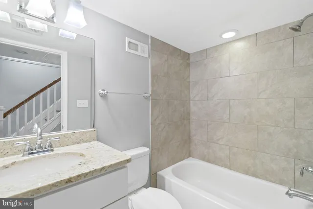 a bathroom with a granite countertop sink a toilet and bathtub